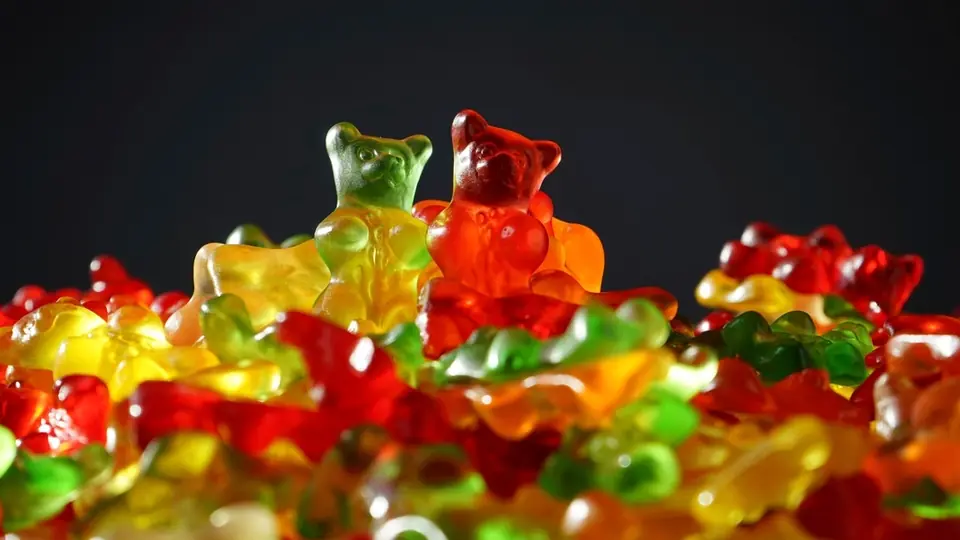 Fruchtgummibärchen in Rot, Gelb und Grün vor dunklem Hintergrund