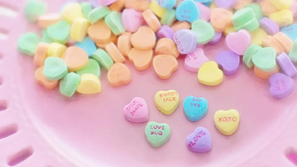 Herzbonbons in Pastellfarben auf einem rosa Teller